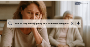 Middle-aged daughter sitting at a kitchen table with her head in her hand, looking guilty, while her elderly mother naps peacefully in the background, symbolizing caregiver guilt in dementia care.