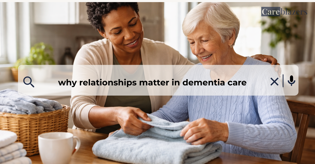 Caregiver and older adult with dementia folding laundry together at a kitchen table, sharing a calm and supportive moment of connection.